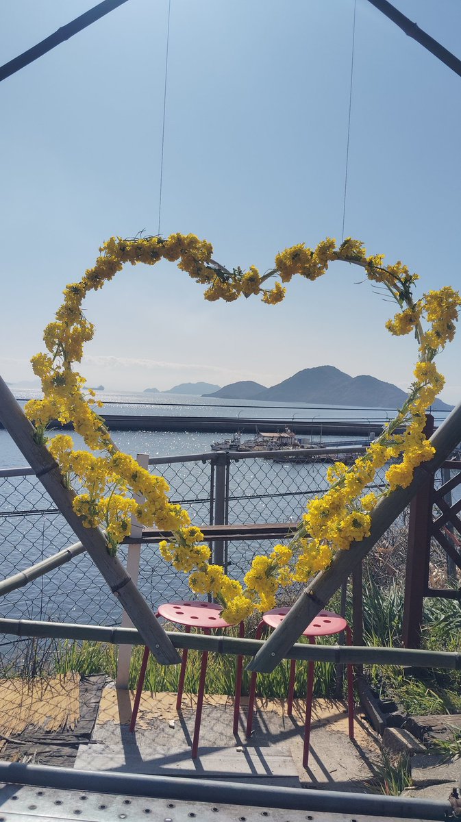 ハート型菜の花アーチから望む瀬戸内海の景色。花で作られたフレーム越しに島々と海が広がり、フォトジェニックなスポット