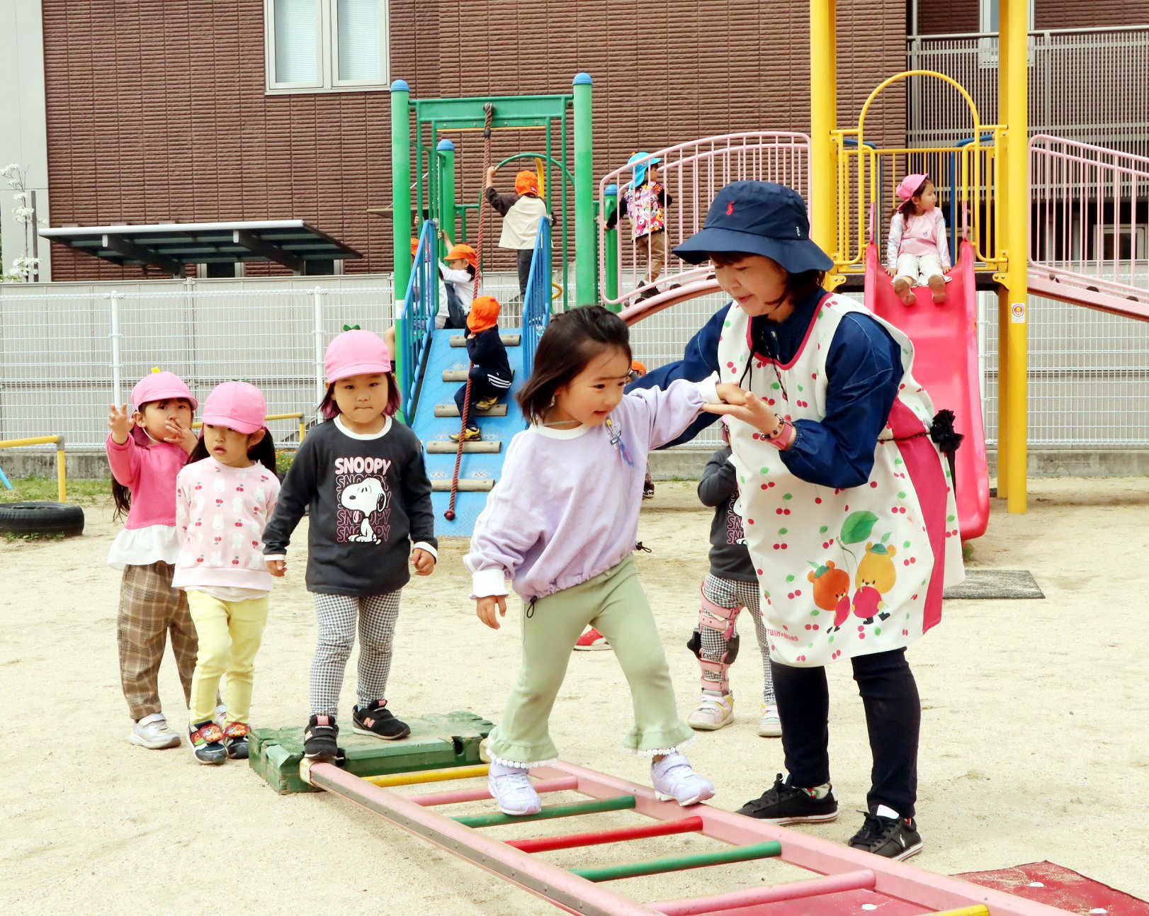 福山市内の認可保育施設で遊ぶ園児と、保育料引き下げ検討に関する専門家会議の初会合の様子を組み合わせた報道写真。