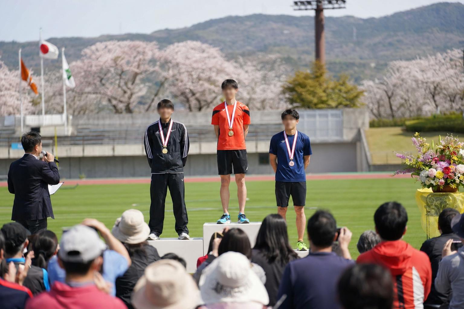 スタジアムでの表彰式のイメージ。メダルを受け取る選手たちと観客の雰囲気（特定の実在人物・実名の再現ではありません）。