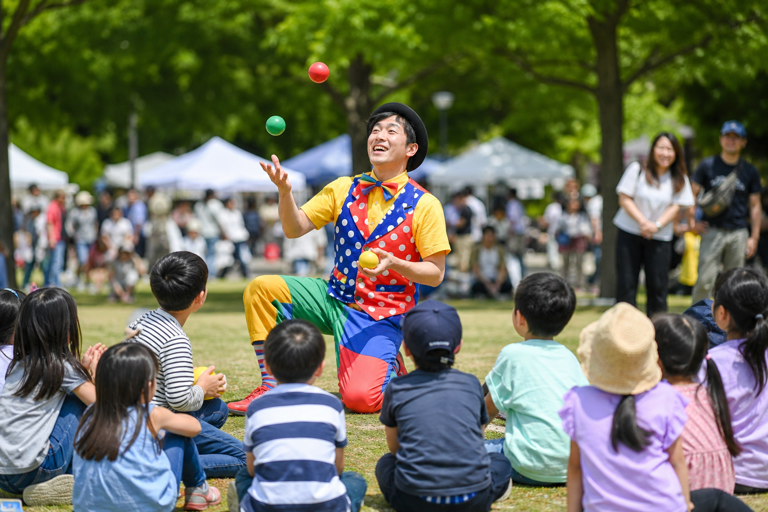 公園の芝生で大道芸を楽しむ家族向けのイメージ。ジャグリングなどのパフォーマンス。※特定の出演者の肖像ではありません。生成AIイメージです